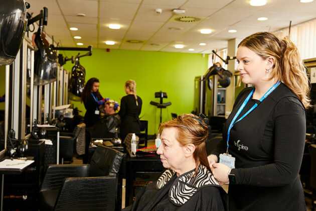 A hairdressing student stood behind a client