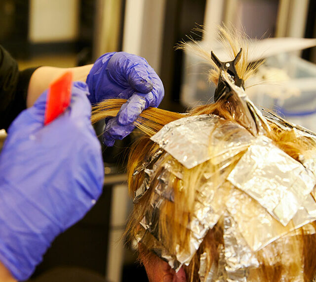 A close up of a client's head with highlighting foils in