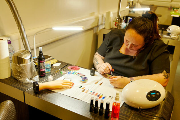 A student sat at a desk working on nail art