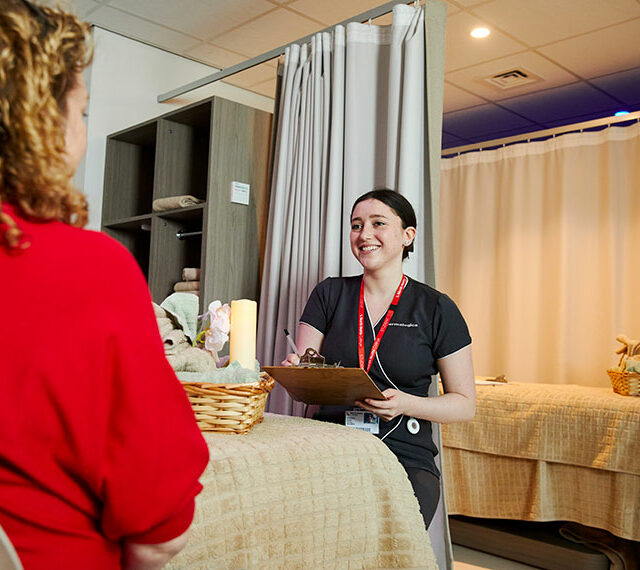 A smiling student stood with a clipboard looking at a client