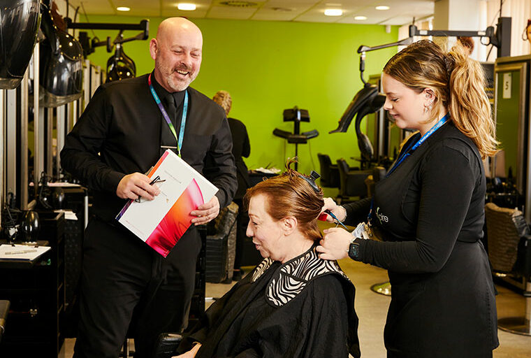 A student trimming a client's hair with a tutor stood close by
