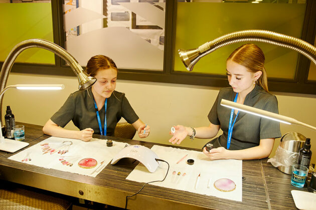 Two students working on nail art at a desk