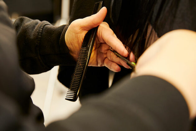 A close up of someone cutting a client's hair